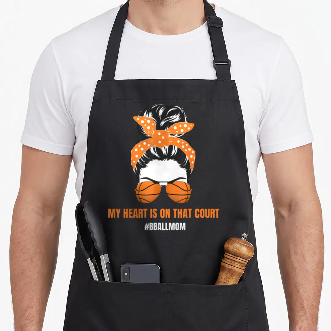Bball messy aprons - Woman with bun, polka dot bandana, basketball sunglasses, and court quote text — shown on a black cotton canvas apron against a white background