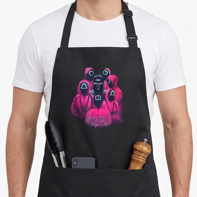 Guard ring apron - Pink masked guards with triangle square circle masks and SQUID GAME logo — shown on a black cotton canvas apron against a white background