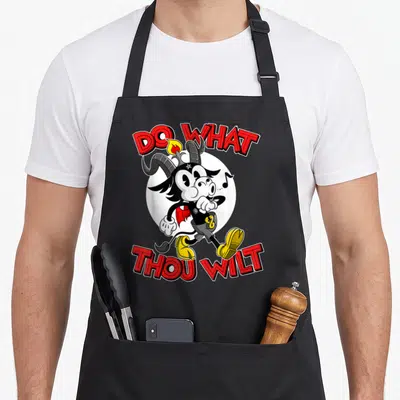 Thou cartoon apron - Cartoon goat running in front of white circle with red DO WHAT THOU WILT text — shown on a black cotton canvas apron against a white background