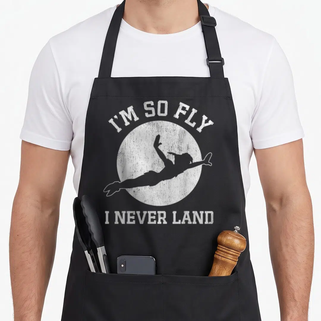 Peter moon apron - I'M SO FLY I NEVER LAND text with grey flying silhouette inside white circle — shown on a black cotton canvas apron against a white background