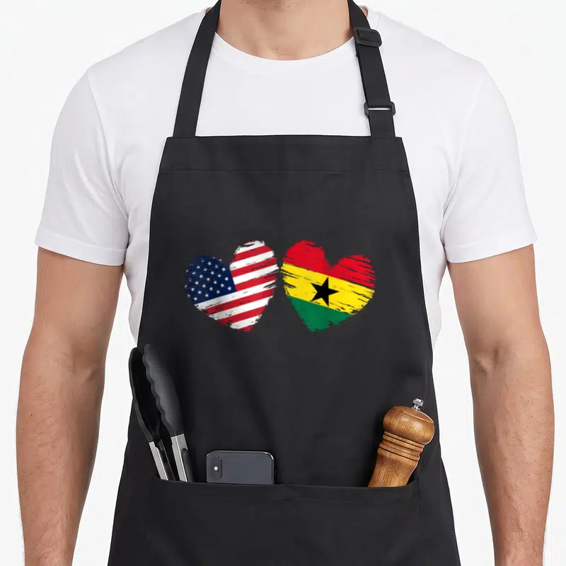 Ghana valentine's day apron - Two hearts side-by-side filled with USA and Ghana flag colors red white blue yellow green — shown on a black cotton canvas apron against a white background
