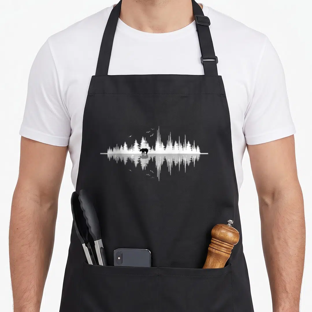 Nature sound waves apron - Black bear silhouette in white forest sound wave pattern with vertical mirror reflection — shown on a black cotton canvas apron against a white background