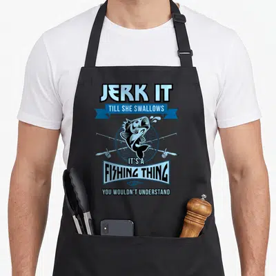 Jerk fishing aprons - Cartoon fish jumping in front of net with crossed rods and pun text — shown on a black cotton canvas apron against a white background