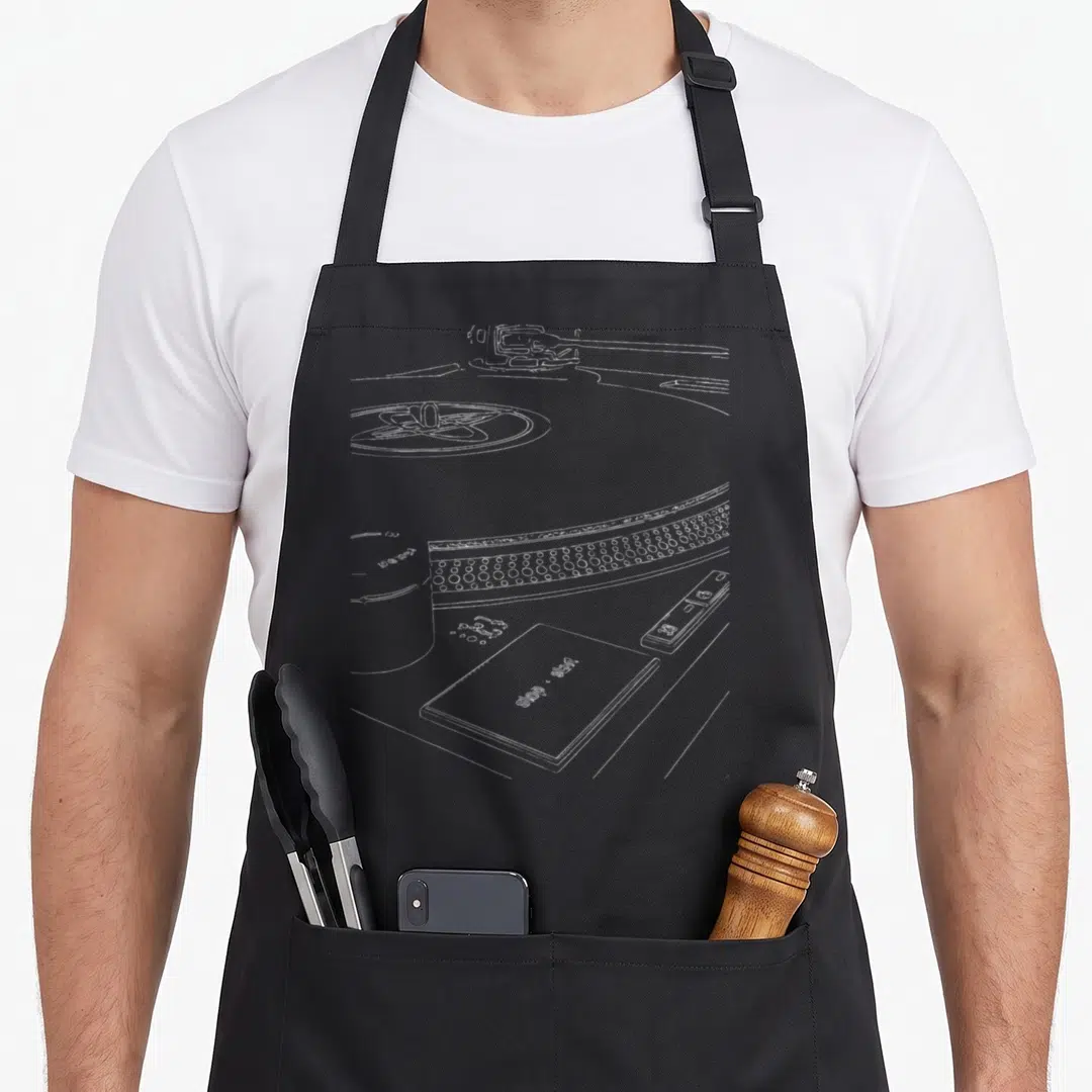 Forever vinyl apron - White line drawing of a DJ turntable with stop and start text on a sleeve — shown on a black cotton canvas apron against a white background