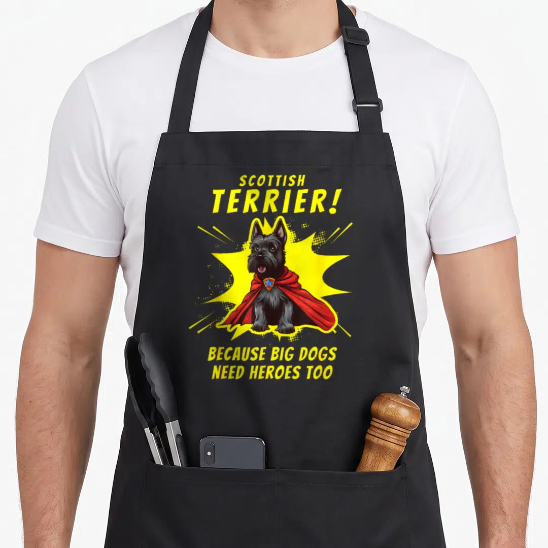 Superdog dog apron - Cartoon Scottish Terrier in red cape with yellow burst and hero text — shown on a black cotton canvas apron against a white background