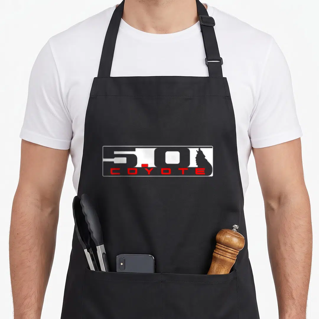 S550 coyote apron - White 5.0 text with red COYOTE label and grey coyote head silhouette in rectangular border — shown on a black cotton canvas apron against a white background