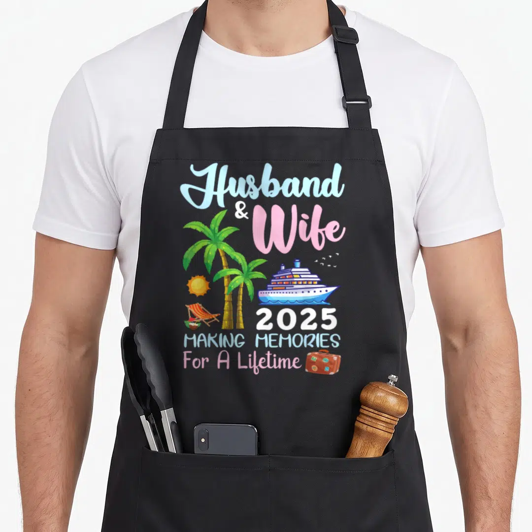 B2shop memory apron - Cartoon cruise ship with palm trees, suitcase, and text Husband Wife 2025 Making Memories — shown on a black cotton canvas apron against a white background