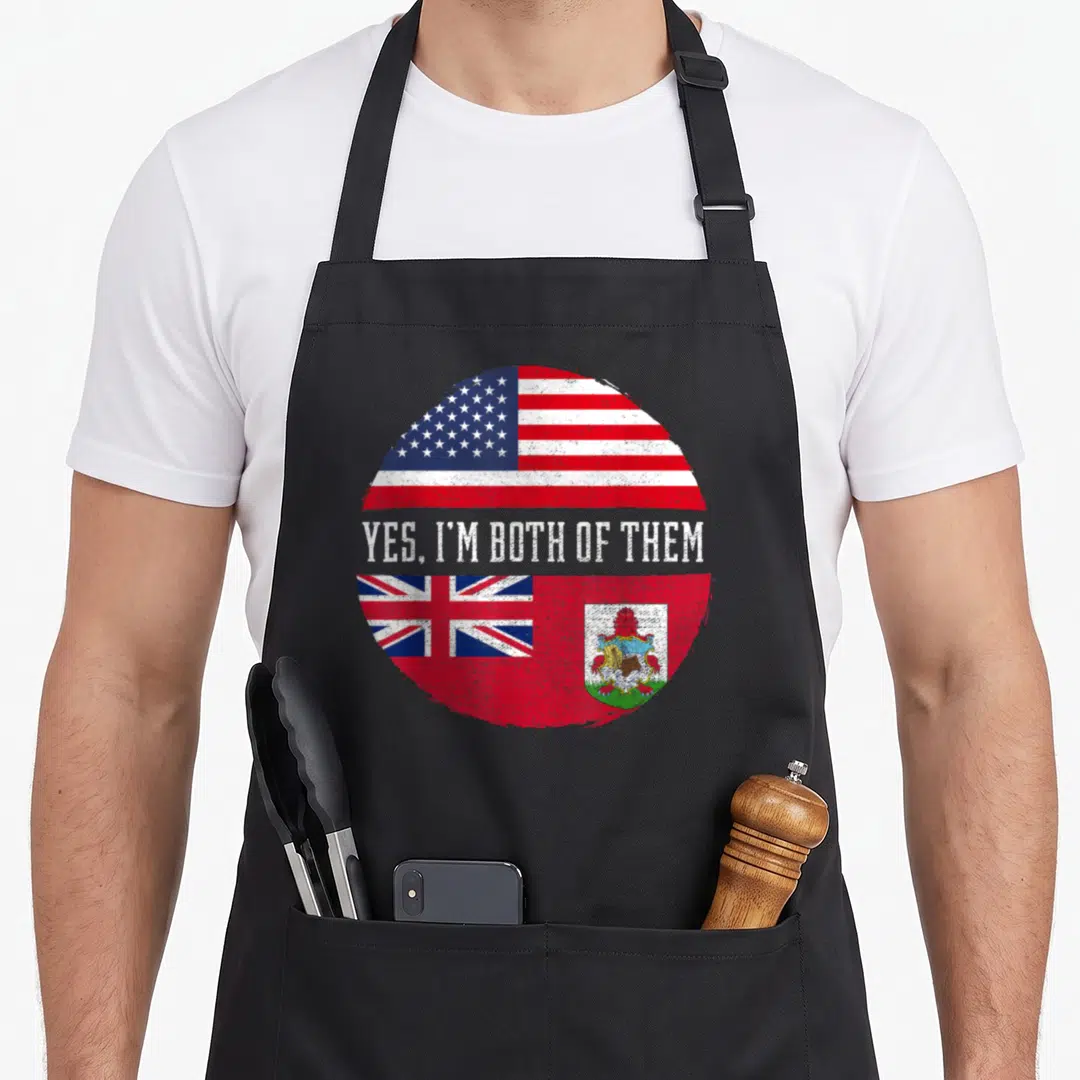 Bermudian american flag apron - Circular split USA and Bermuda flag design with distressed white text YES I'M BOTH — shown on a black cotton canvas apron against a white background