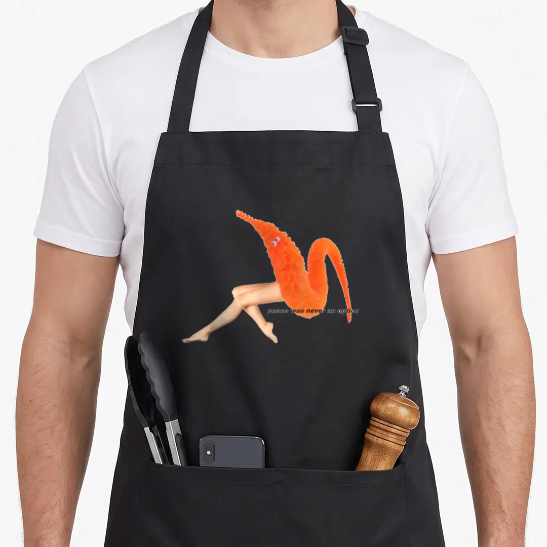 Worm meme apron - Orange fuzzy worm with human legs sitting down next to text peace was never an option — shown on a black cotton canvas apron against a white background