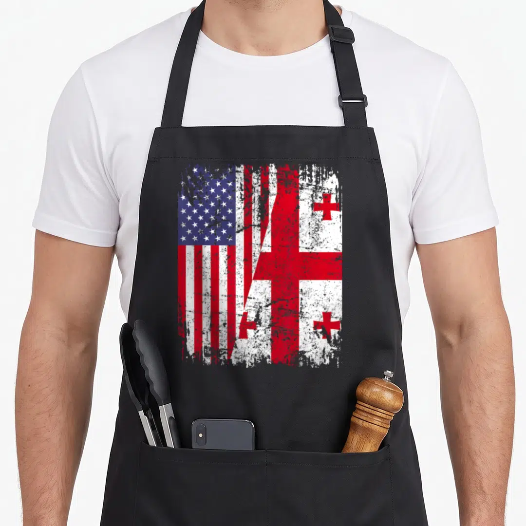 Georgian american flag apron - Two flags split diagonally in red white blue distressed texture — shown on a black cotton canvas apron against a white background