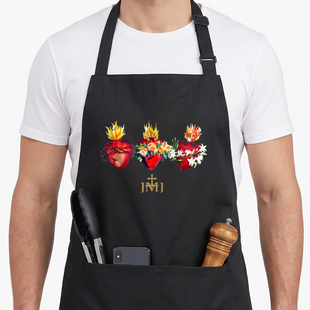 Three catholic apron - Three red hearts with thorns roses lilies and gold JMJ text in watercolor — shown on a black cotton canvas apron against a white background