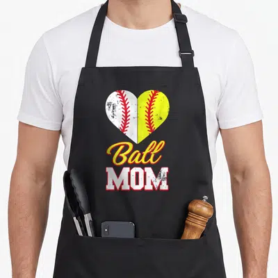 Ball baseball apron - Split heart with white baseball and yellow softball above Ball MOM text — shown on a black cotton canvas apron against a white background