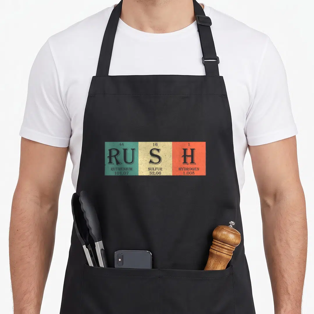 Fan chemistry apron - Three teal yellow orange squares with Ru S H chemical symbols and atomic data — shown on a black cotton canvas apron against a white background