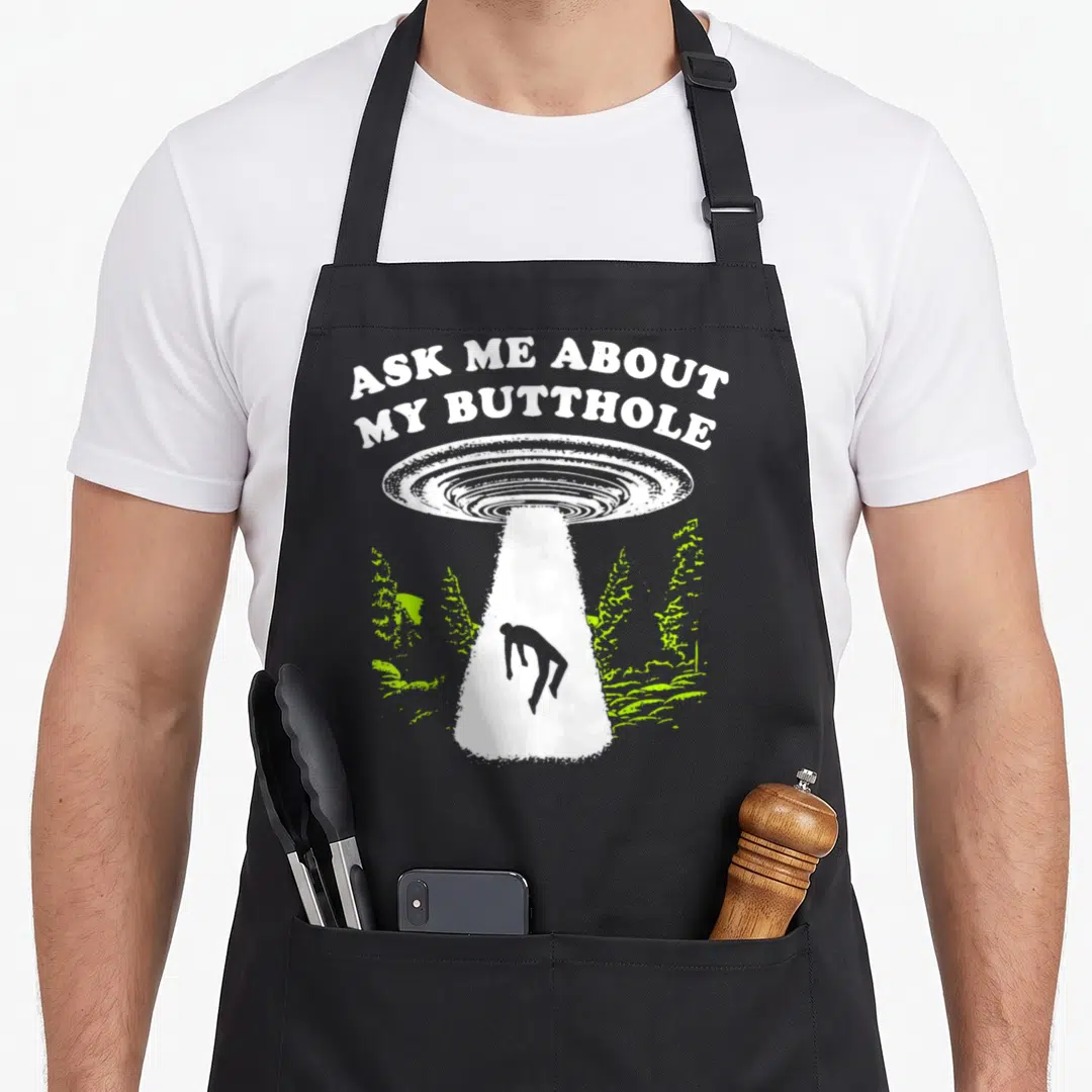 Butthole ask about apron - UFO beam lifting person under arched text ASK ME ABOUT MY BUTTHOLE with lime plants — shown on a black cotton canvas apron against a white background