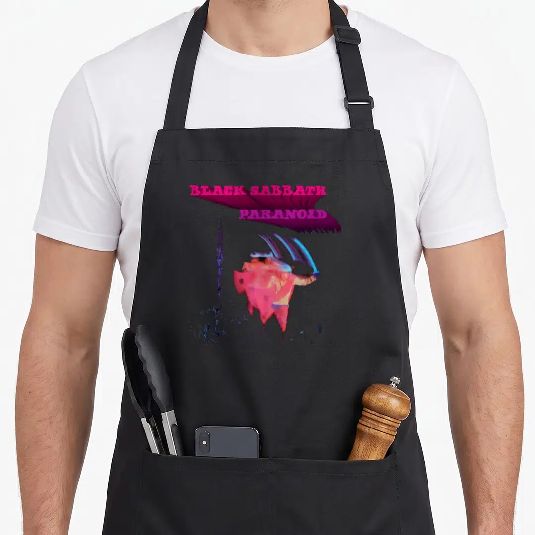 Paranoid black sabbath apron - Surreal figure with blue wings below pink BLACK SABBATH text and purple abstract shape — shown on a black cotton canvas apron against a white background