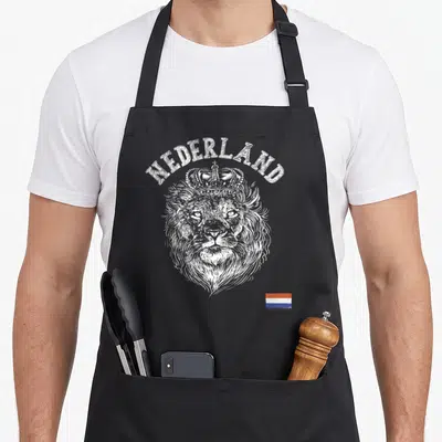 Nederland dutch apron - Crowned lion head with NEDERLAND text and red white blue flag in white line art — shown on a black cotton canvas apron against a white background