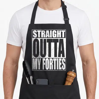Outta forty birthday apron - Stacked white and grey text reading straight outta my forties inside a rectangular border — shown on a black cotton canvas apron against a white background