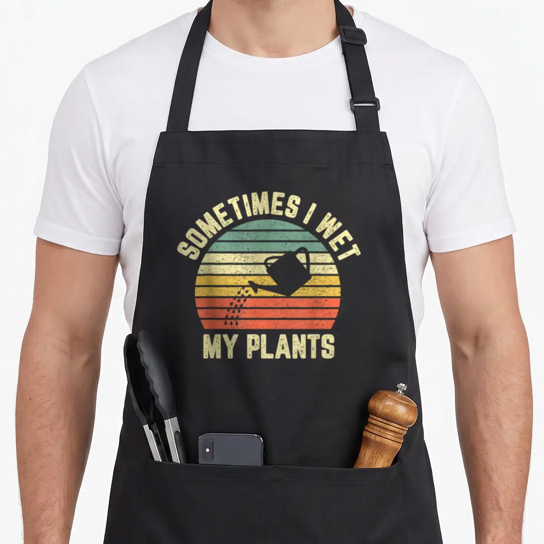 Gardening plant apron - Retro striped sun with watering can and SOMETIMES I WET MY PLANTS text — shown on a black cotton canvas apron against a white background