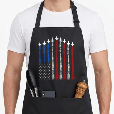 Airplane 4th of july apron - Nine jets leaving red white and blue smoke trails forming vertical stripes and a star — shown on a black cotton canvas apron against a white background