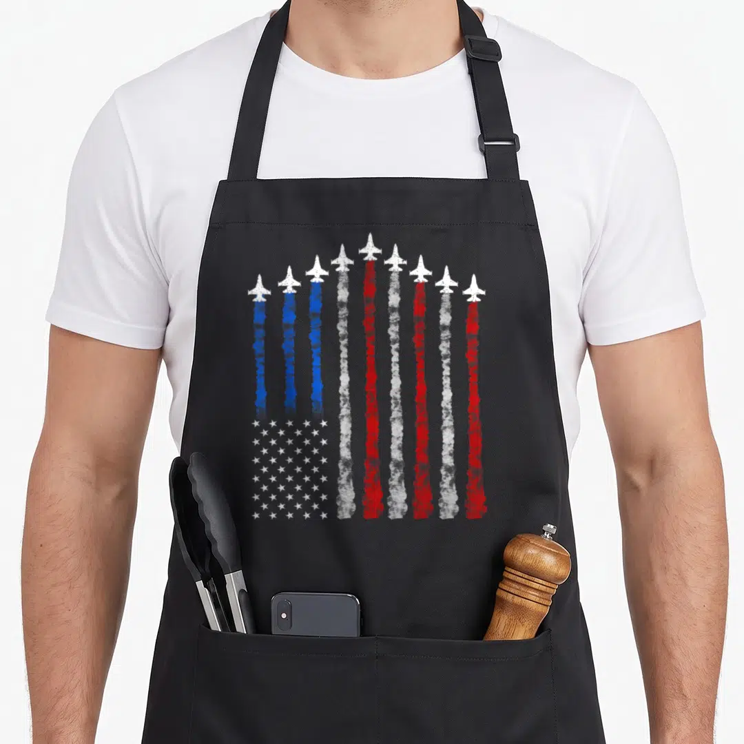 Airplane 4th of july apron - Nine jets leaving red white and blue smoke trails forming vertical stripes and a star — shown on a black cotton canvas apron against a white background