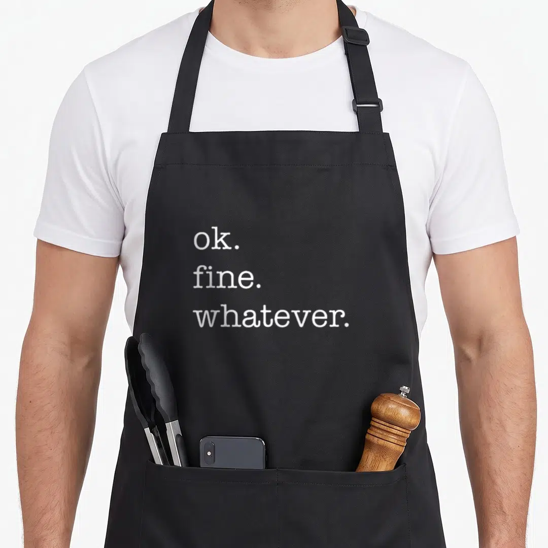 Fine whatever apron - White ok fine whatever text stacked on black bib apron — shown on a black cotton canvas apron against a white background