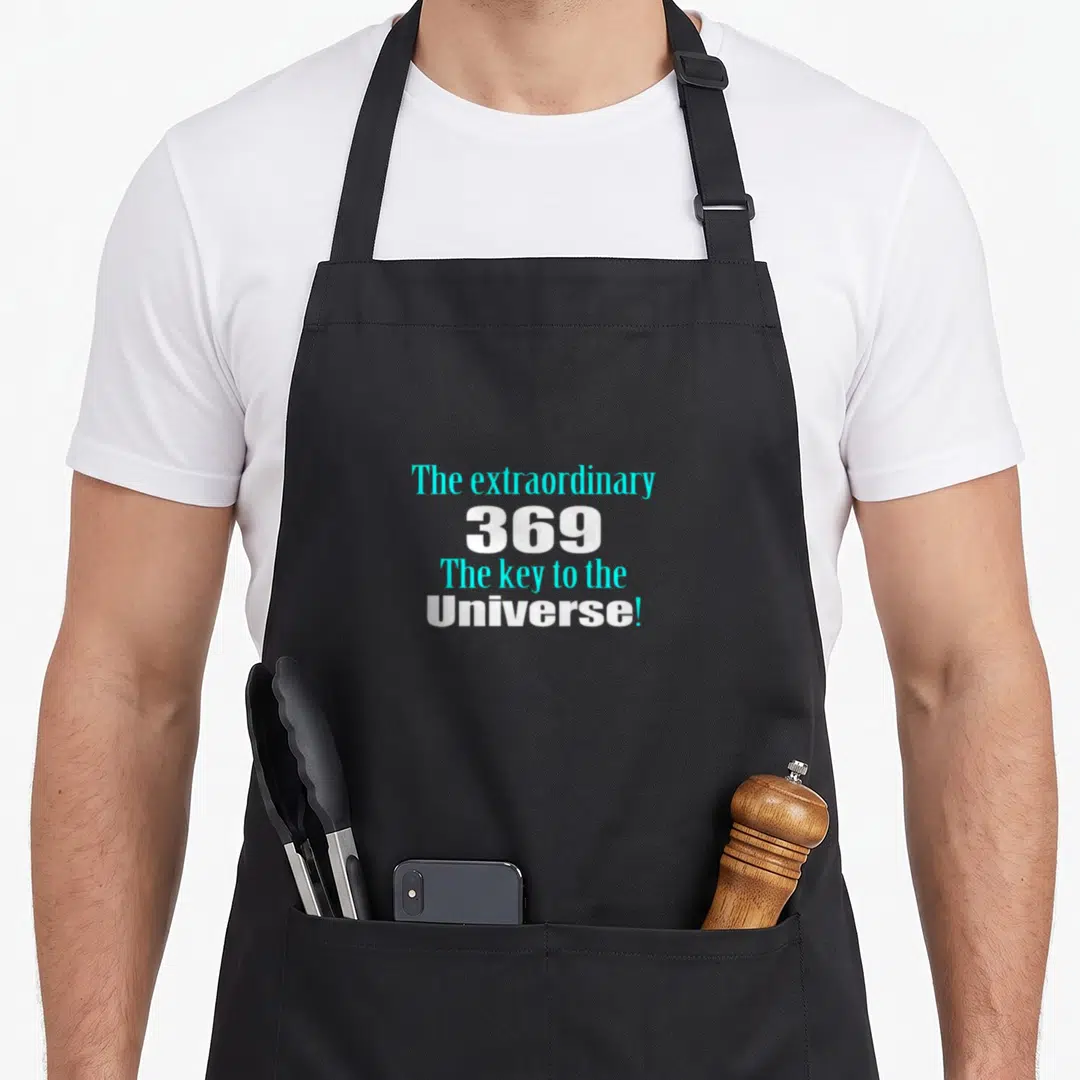 Key manifestation apron - Stacked cyan and white text reading The extraordinary 369 The key to the Universe! — shown on a black cotton canvas apron against a white background