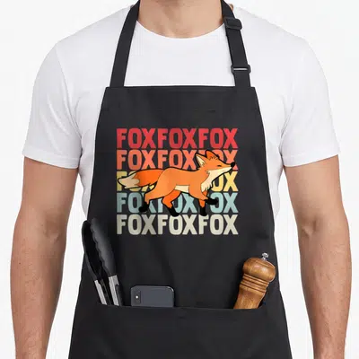 Fox smart apron - Cartoon fox walking over five stacked rows of repeated text in a color gradient — shown on a black cotton canvas apron against a white background