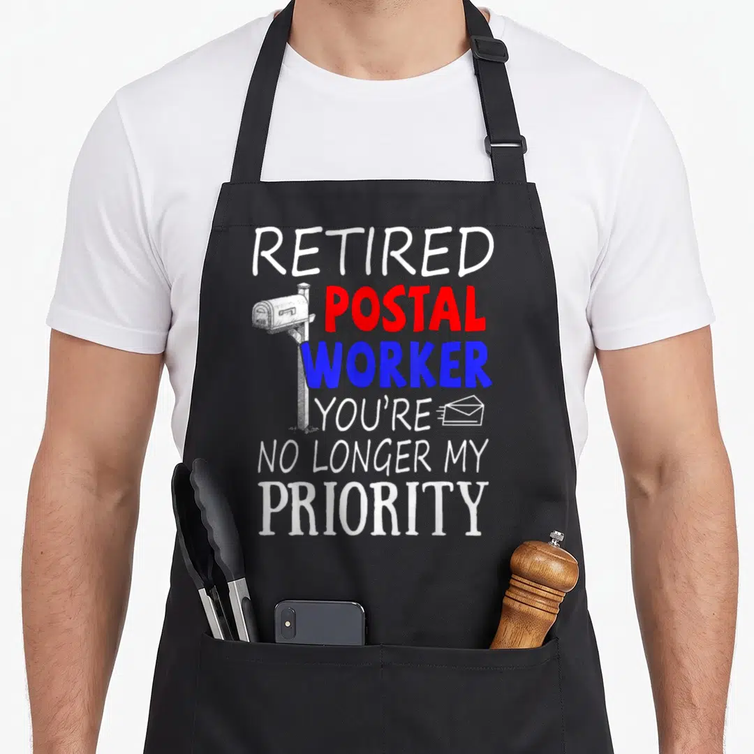 Office retirement apron - Stacked typography reading RETIRED POSTAL WORKER with line-art mailbox and envelope icon — shown on a black cotton canvas apron against a white background