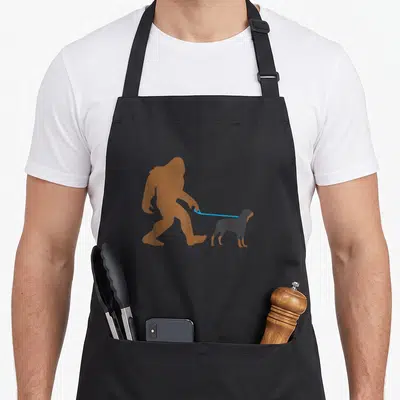 Rottweiler walking apron - Brown Bigfoot silhouette holding blue leash attached to dark grey Rottweiler dog standing — shown on a black cotton canvas apron against a white background