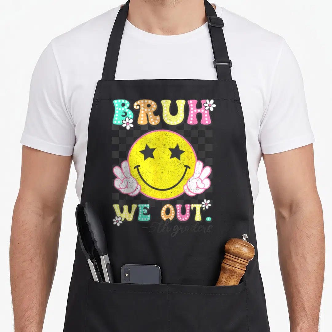 Bruh fifth apron - Retro yellow smiley face with star eyes and peace hands over checkerboard with BRUH WE OUT text — shown on a black cotton canvas apron against a white background