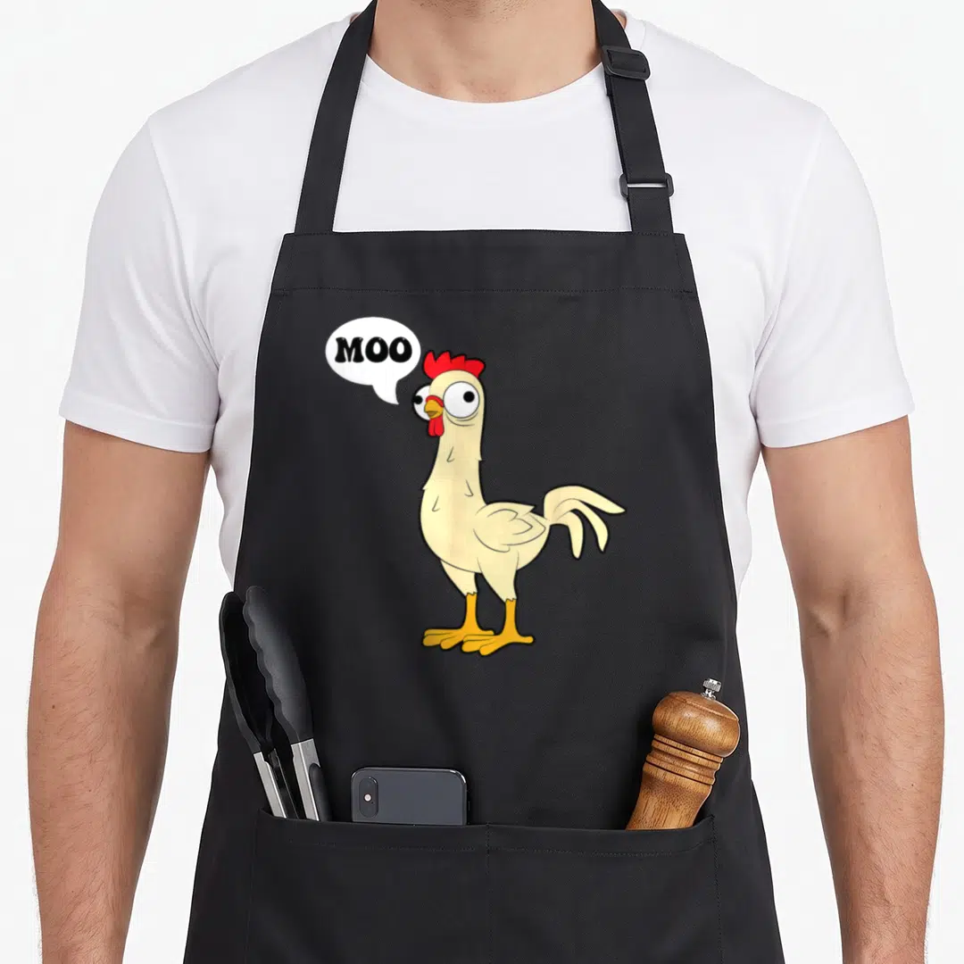 Fowl hen apron - Cartoon chicken with red comb saying MOO in white speech bubble — shown on a black cotton canvas apron against a white background