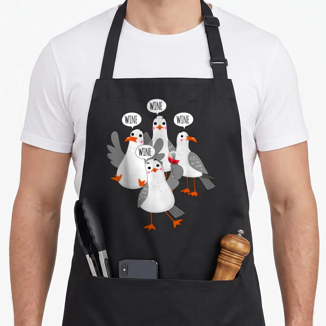 Seagull wine apron - Four cartoon seagulls with WINE speech bubbles and a red wine glass — shown on a black cotton canvas apron against a white background