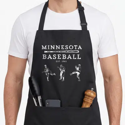 Fan minnesota apron - White distressed text MINNESOTA BASEBALL EST 1961 with three baseball player silhouettes — shown on a black cotton canvas apron against a white background