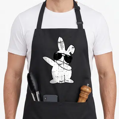 Outfit easter bunny aprons - White cartoon rabbit wearing black sunglasses and extending one arm in a dab pose — shown on a black cotton canvas apron against a white background