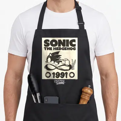 Epic crazy hedgehog apron - Black Sonic running over infinity symbol with 1991 text on cream background — shown on a black cotton canvas apron against a white background