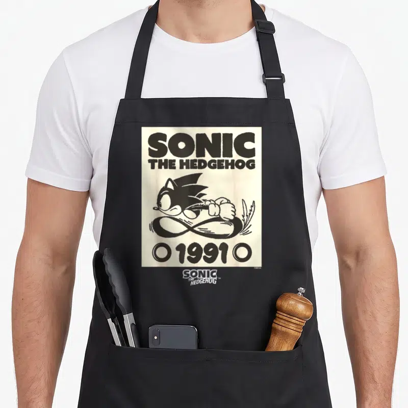 Epic crazy hedgehog apron - Black Sonic running over infinity symbol with 1991 text on cream background — shown on a black cotton canvas apron against a white background