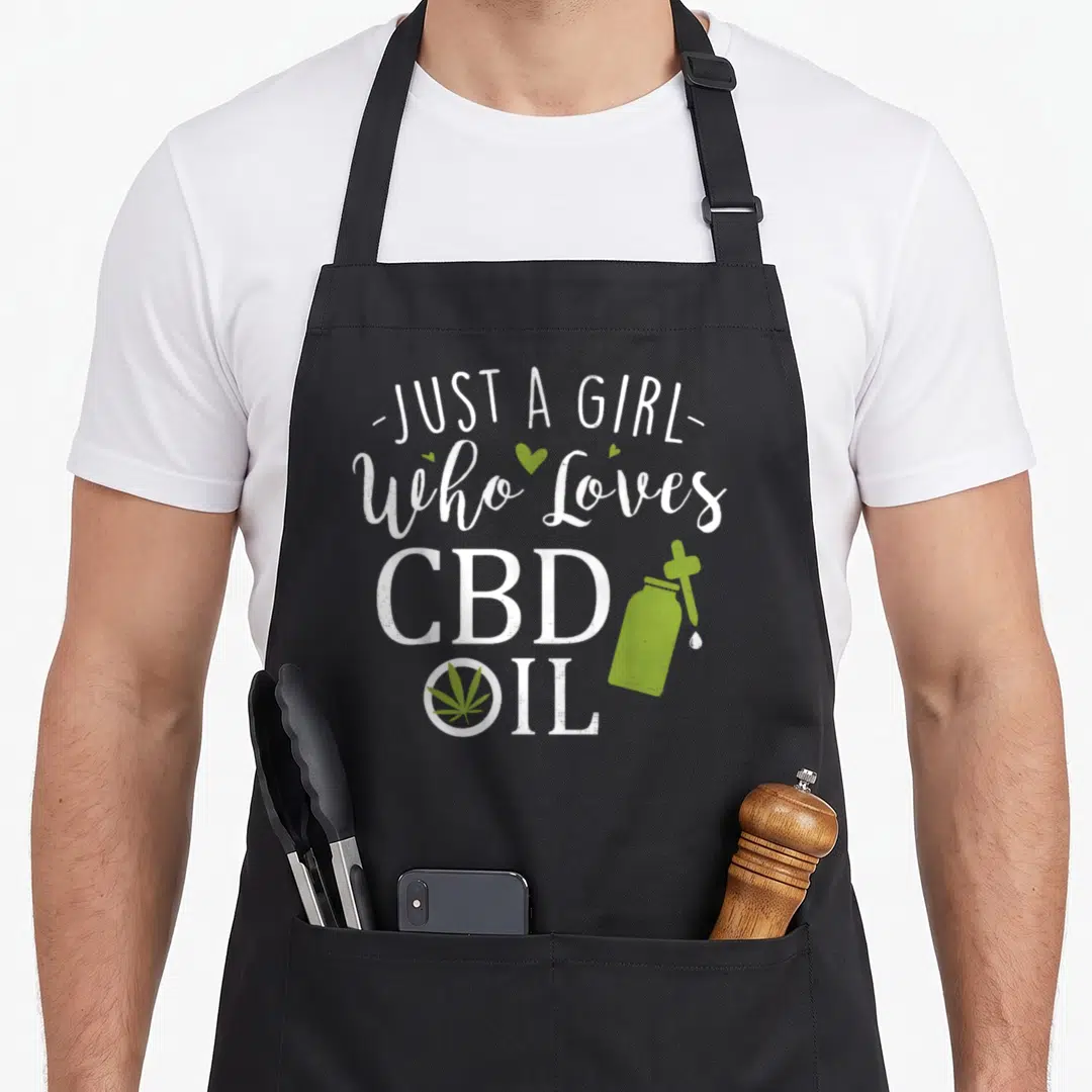 Cbd i love hemp apron - Stacked white text with green CBD bottle, dropper, and cannabis leaf inside the letter O — shown on a black cotton canvas apron against a white background