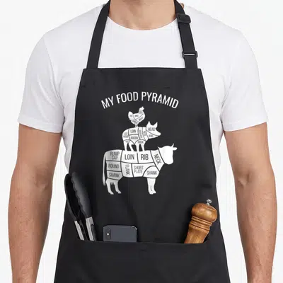 Food chicken apron - White stacked chicken pig cow diagram labeled with meat cuts like loin rib shank and bacon — shown on a black cotton canvas apron against a white background