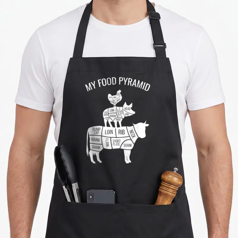 Food chicken apron - White stacked chicken pig cow diagram labeled with meat cuts like loin rib shank and bacon — shown on a black cotton canvas apron against a white background