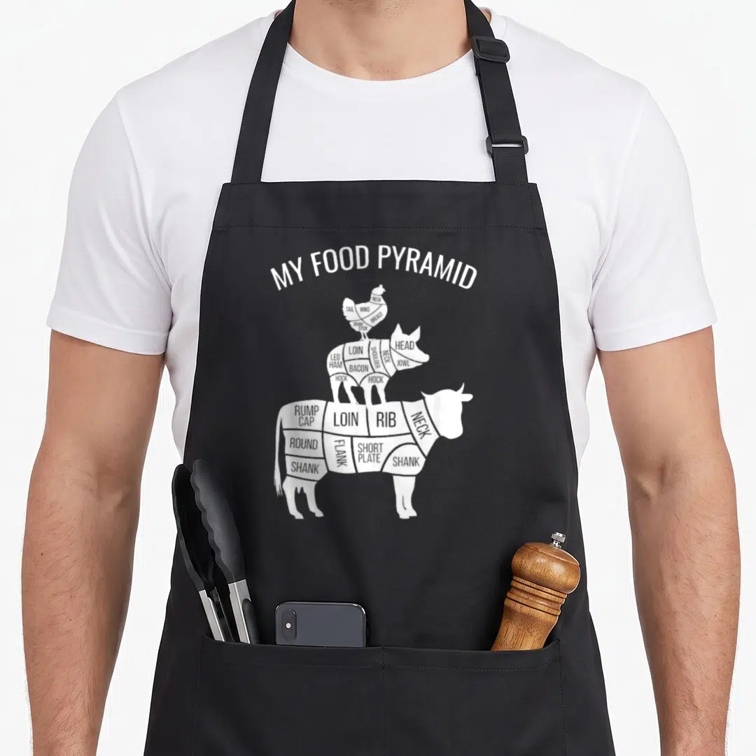 Food chicken apron - White stacked chicken pig cow diagram labeled with meat cuts like loin rib shank and bacon — shown on a black cotton canvas apron against a white background