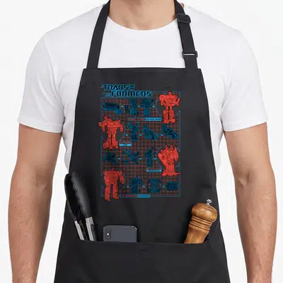 Transform transformer apron - TRANSFORMERS schematic with Autobot and Decepticon robot vehicle forms on blue grid — shown on a black cotton canvas apron against a white background