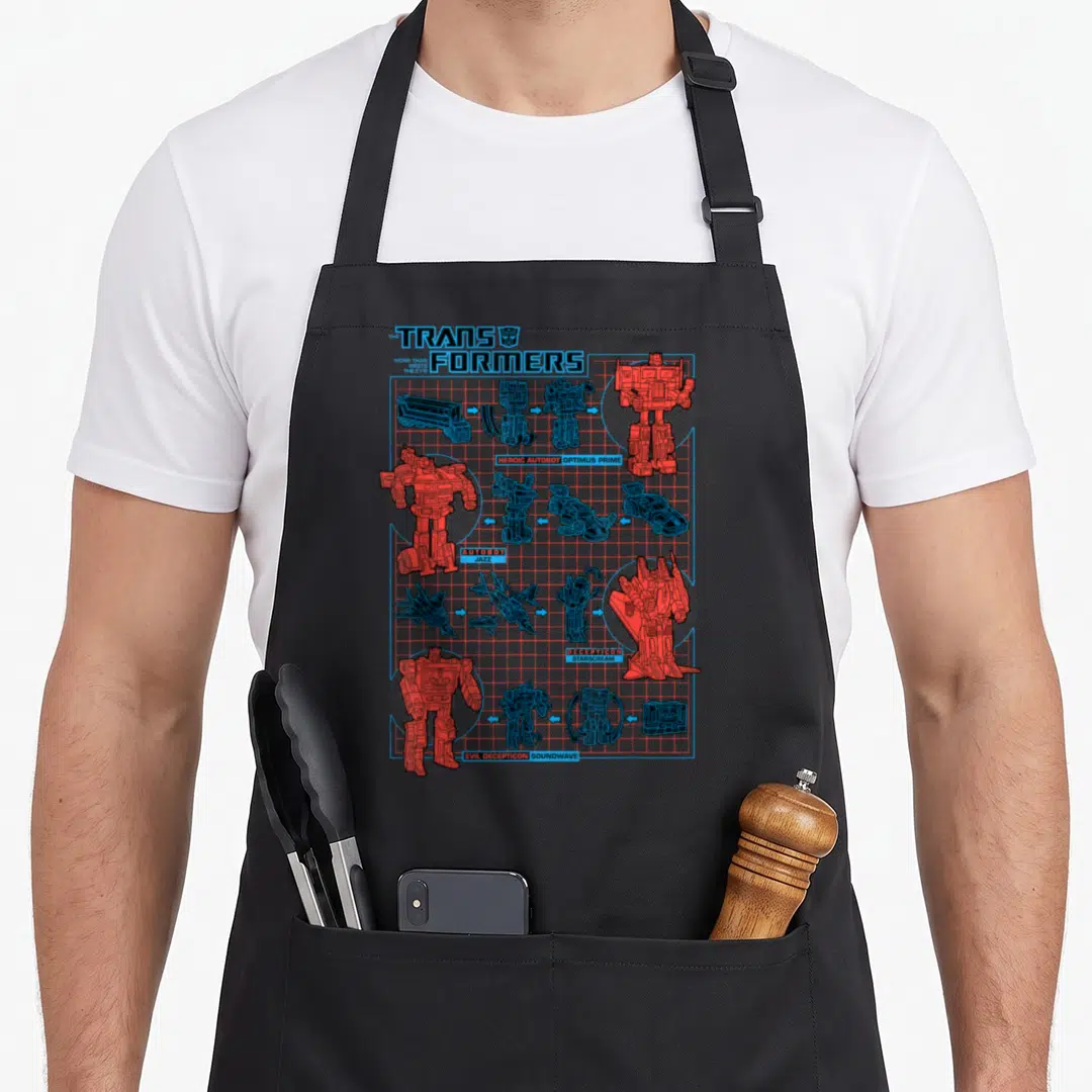 Transform transformer apron - TRANSFORMERS schematic with Autobot and Decepticon robot vehicle forms on blue grid — shown on a black cotton canvas apron against a white background
