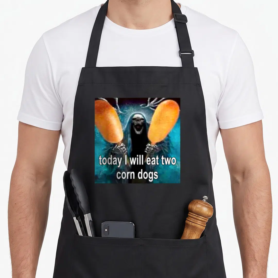 Today dog apron - Grim reaper holding two orange corn dogs with white text on black background — shown on a black cotton canvas apron against a white background