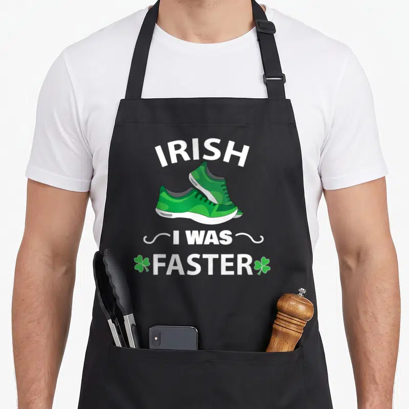 Faster st patrick day aprons - Two green sneakers below arched IRISH text and FASTER flanked by shamrocks — shown on a black cotton canvas apron against a white background