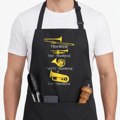 Player bassoon apron - Four yellow brass instruments labeled trombone tiny twisty fat in white text — shown on a black cotton canvas apron against a white background