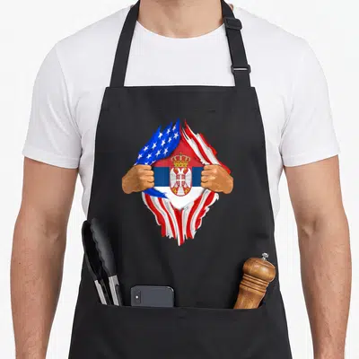 Serbian blood apron - Hands tear American flag to reveal Serbian crown and double-headed eagle shield — shown on a black cotton canvas apron against a white background