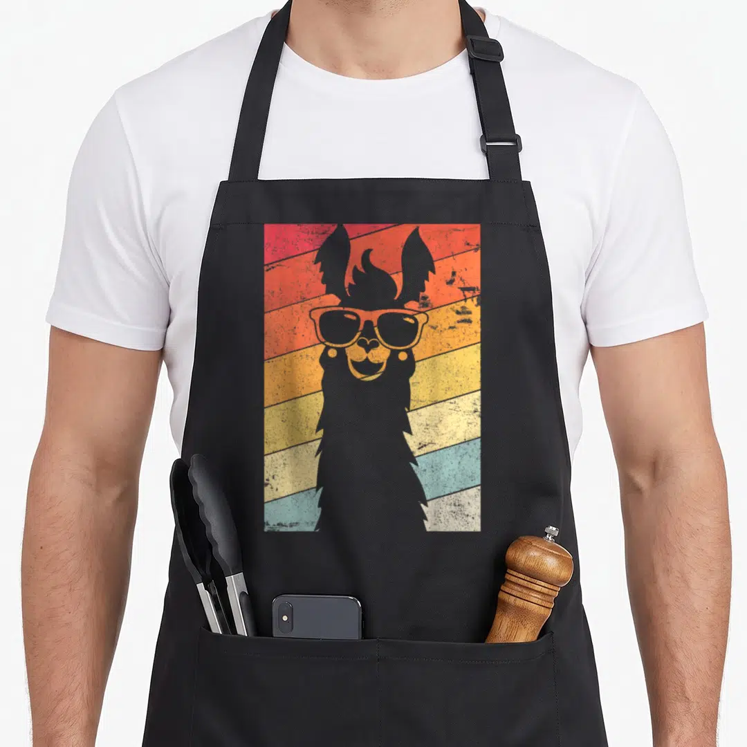 Llama alpaca apron - Grey llama silhouette with sunglasses over red orange yellow blue retro stripes — shown on a black cotton canvas apron against a white background
