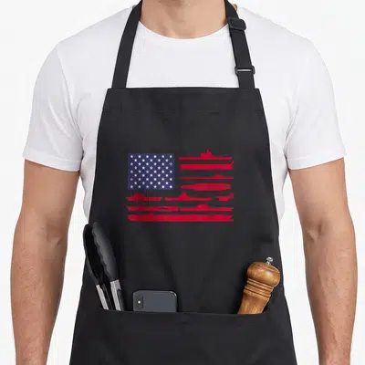 Naval patriotic apron - US flag with red stripes made of naval ship silhouettes in distressed blue and white stars — shown on a black cotton canvas apron against a white background