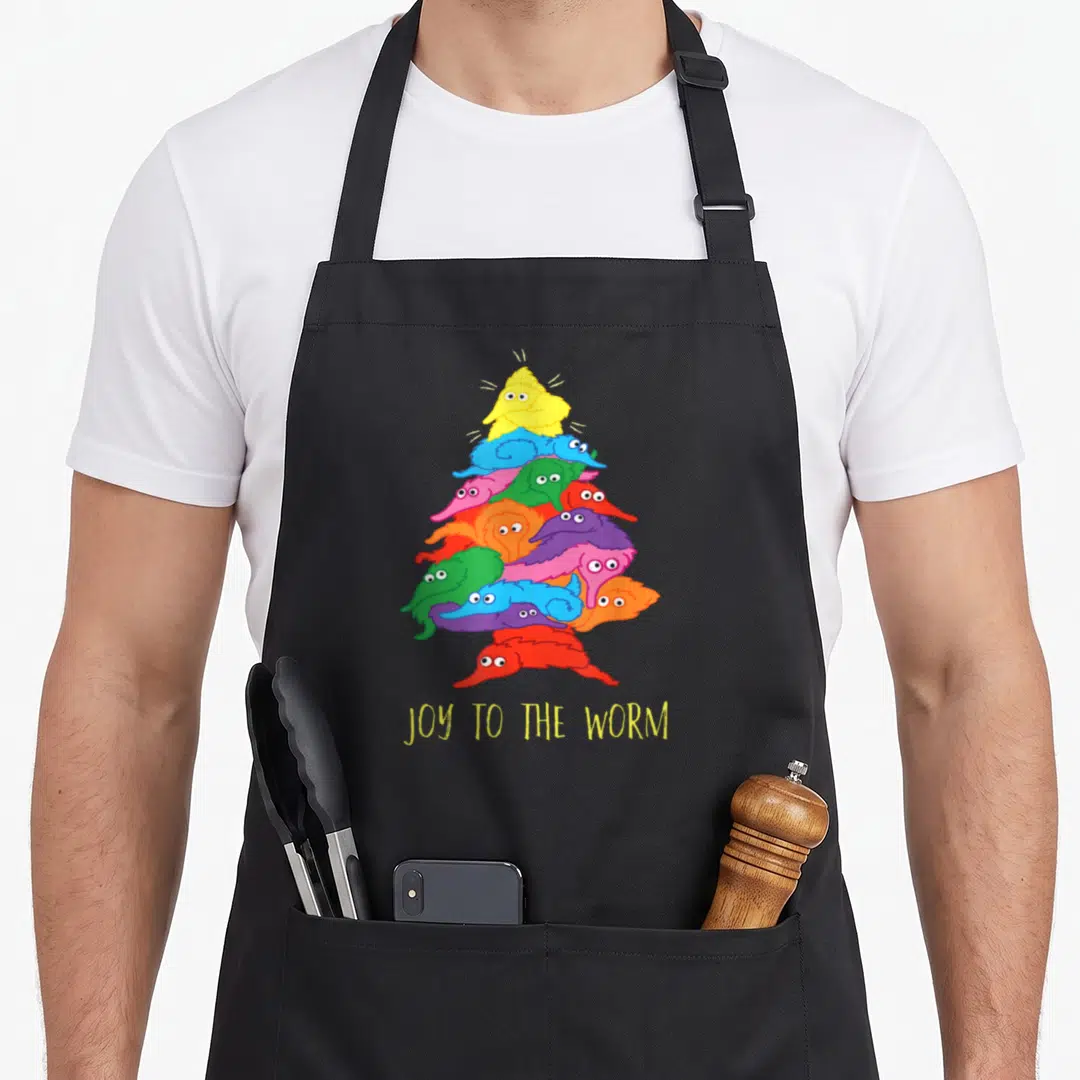 Joy christmas tree apron - Stack of colorful cartoon worms in triangle shape with text JOY TO THE WORM below — shown on a black cotton canvas apron against a white background