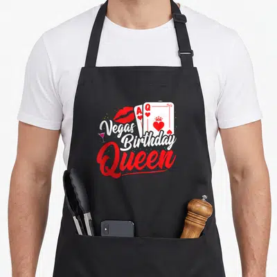 Trip queen birthday apron - Playing cards, red lips, cocktail glass, and stacked text reading Vegas Birthday Queen — shown on a black cotton canvas apron against a white background
